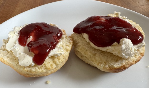 A plate with two scones topped with cream and strawberry jam.