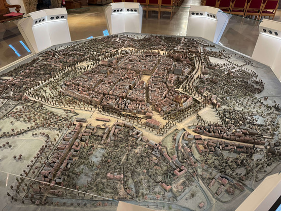The picture shows a detailed model of the city of Leipzig, which is on display in the Museum im Alten Rathaus in Leipzig. The model shows a historical view of the city and provides a comprehensive overview of the city's architecture and structure in the past.

The model is placed on a large table and shows the city with its numerous buildings, streets, squares and green spaces. The buildings are reproduced in great detail and true to scale, with the city walls, towers and characteristic buildin…