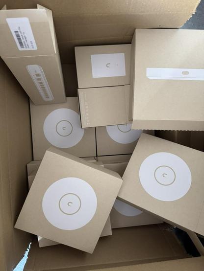 Various boxes of Ubiquiti Unifi equipment. Among others, several Unifi U7 devices, fiber gateways and accessories.